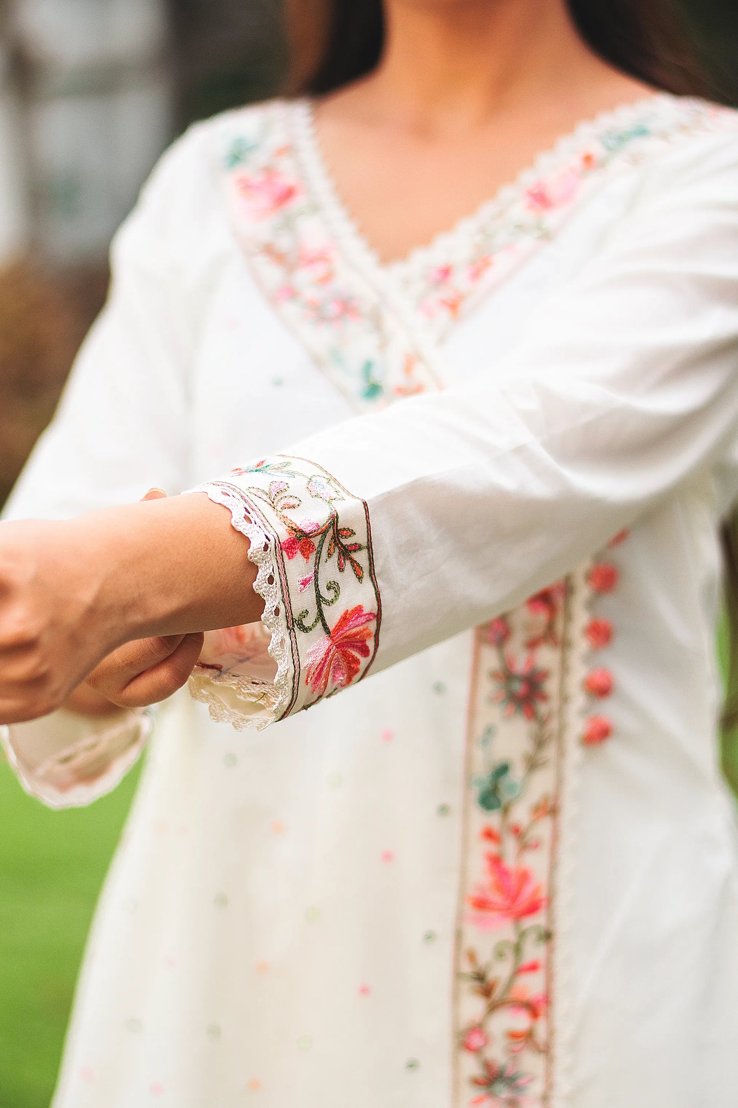 An Indian woman's hand, resting gently on the side of an off-white cotton angarkha