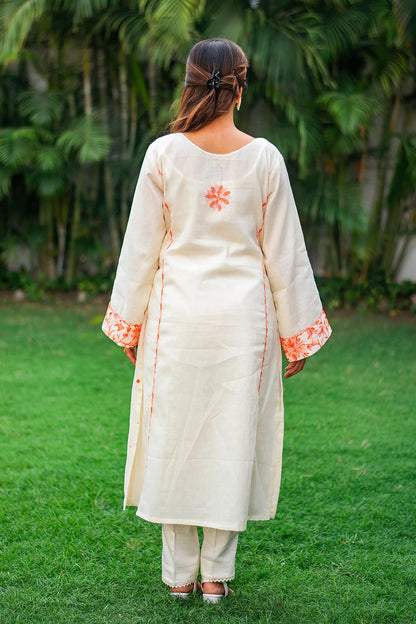 Back view of an Indian model wearing an off-white kurta with peach embroidery and matching trousers.