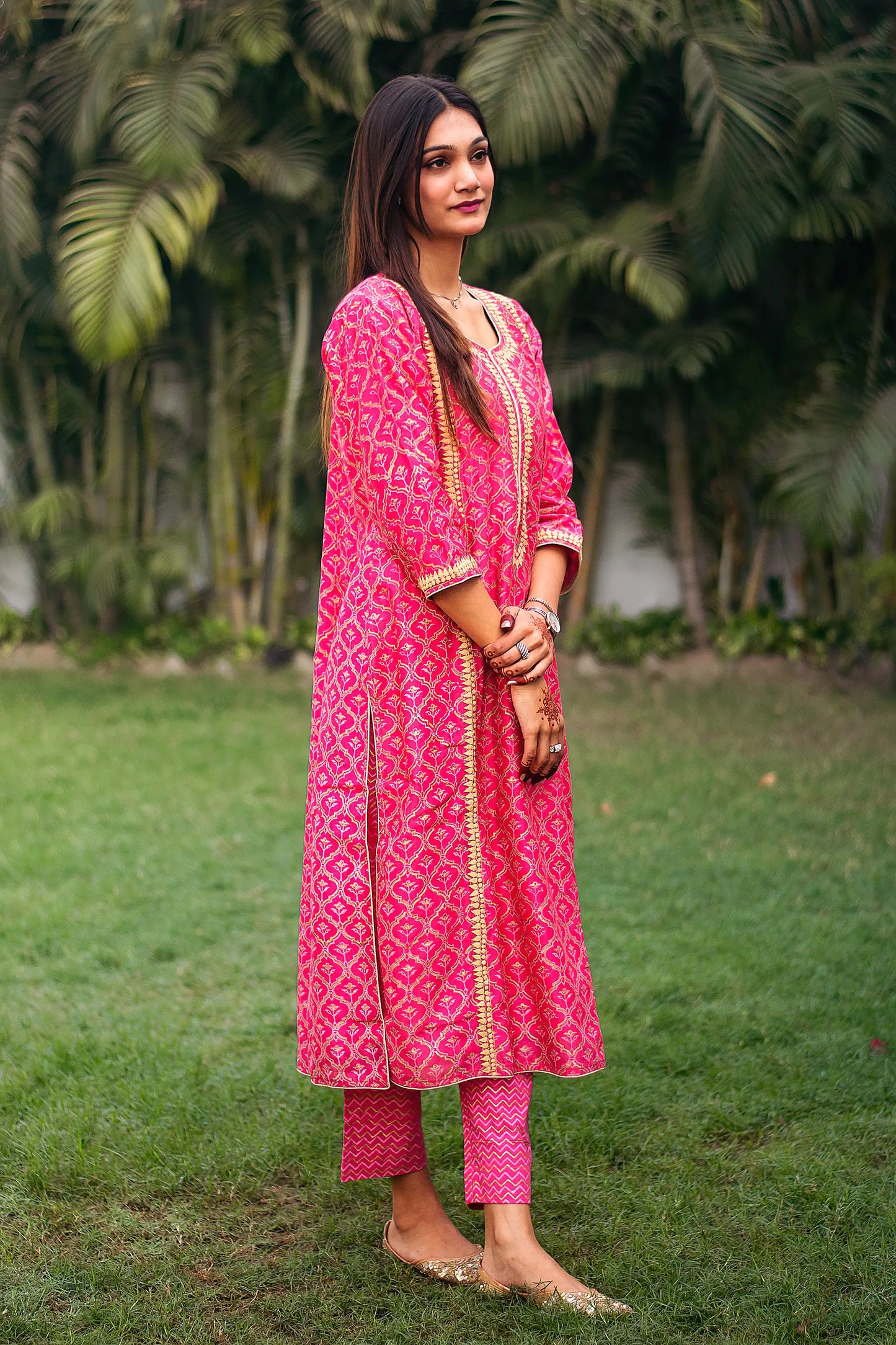 ndian model in a side pose while wearing the magenta kalidar kurta with beige applique motifs and magenta foil-printed trousers.