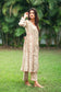 An indian woman wearing a printed staple tussar gold A line kurta and trousers.An indian woman wearing a printed staple tussar gold A line kurta and trousers with gold chanderi dupatta. The A line kurta has double kali in red colour. The  woman show case the entire ensemble from her right.
