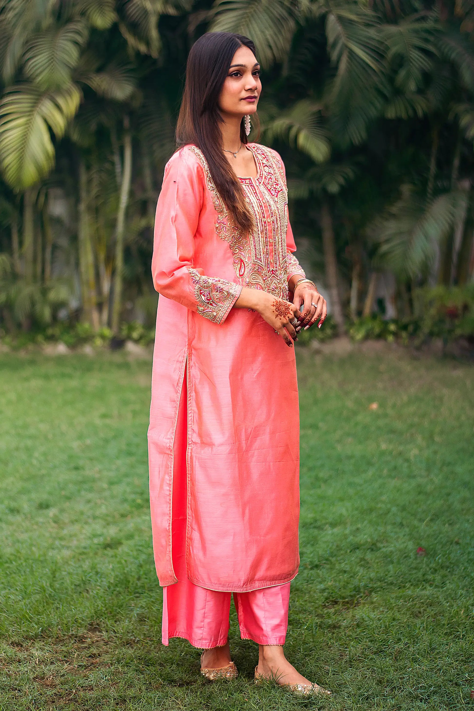 Indian model in a side pose, wearing a peach kurta with dense zardozi embroidery and peach palazzo.