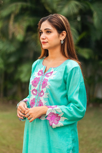 Side profile of an Indian model wearing a blue chanderi kurta with purple patchwork flowers and pink piping.