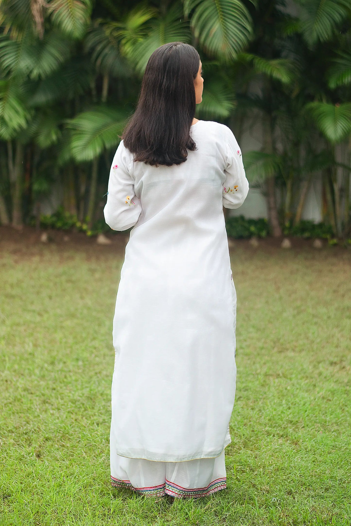 Back view of an Indian model wearing a white chanderi kurta with resham embroidery, paired with white palazzo.