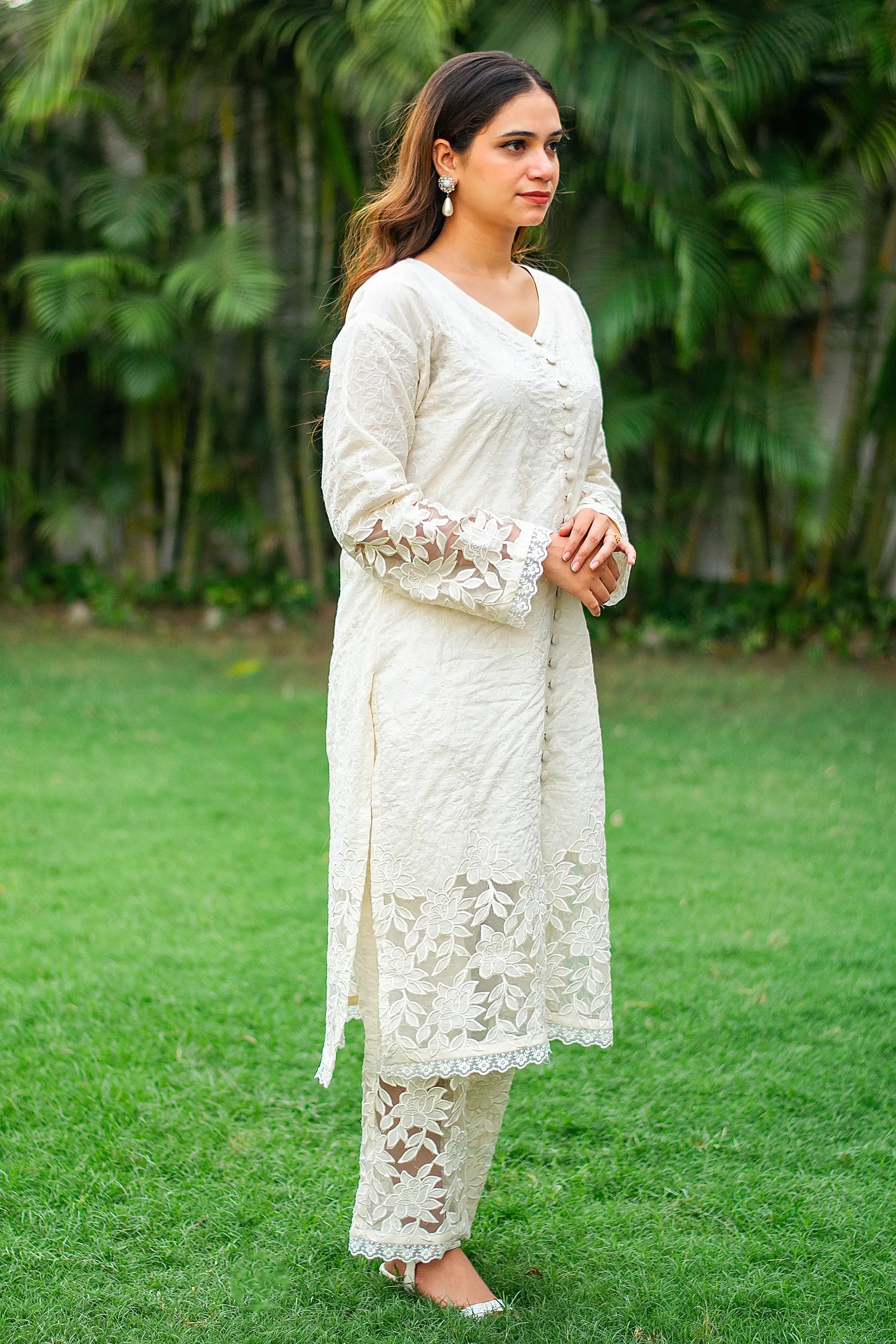 ndian model in a side profile, wearing a white cutwork kurta with matching pants.