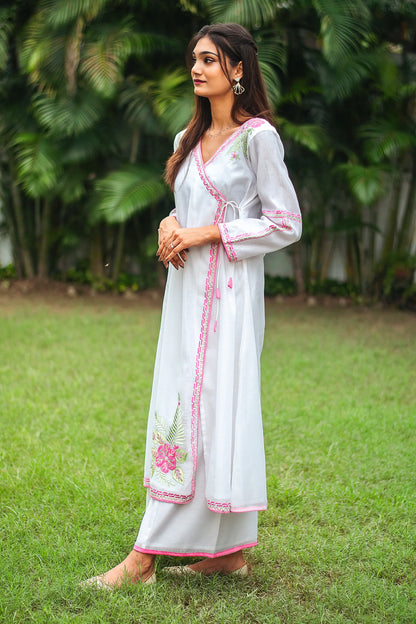 Side view of an Indian model wearing a white chanderi angrakha with pink flowers and green leaves, along with white palazzo