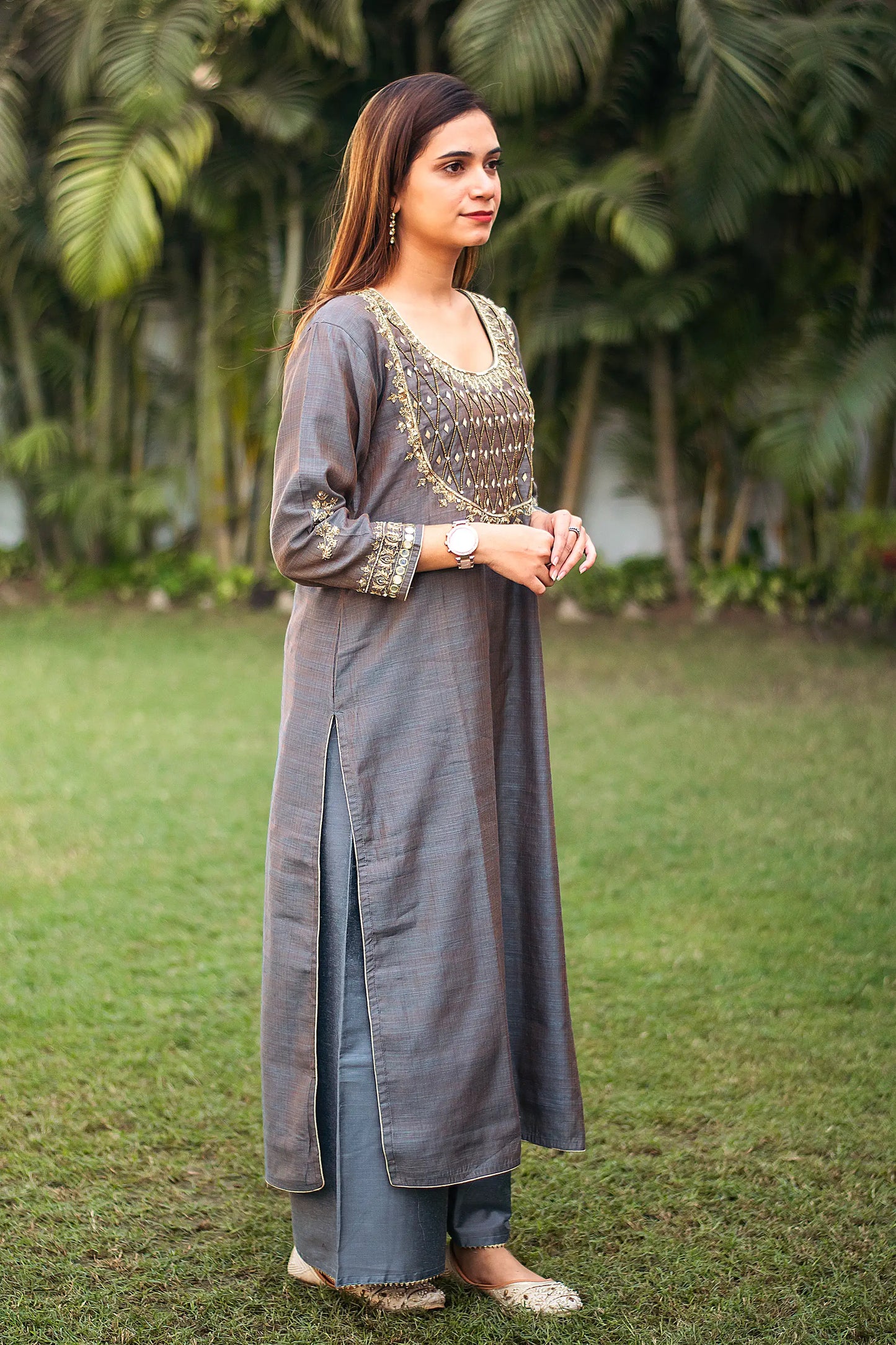 Indian model in a side pose, wearing a grey silk kurta with golden embroidery, paired with grey palazzo.