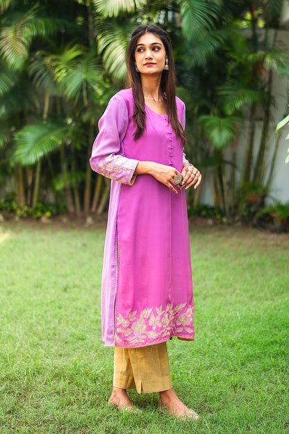 Side pose of an Indian model wearing a light purple organza kurta with golden floral cutwork at the hem, complemented by gold trousers.