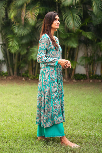 Indian model in a side pose,wearing the grey and green ikat print kurta with delicate applique detailing, paired with green palazzo.