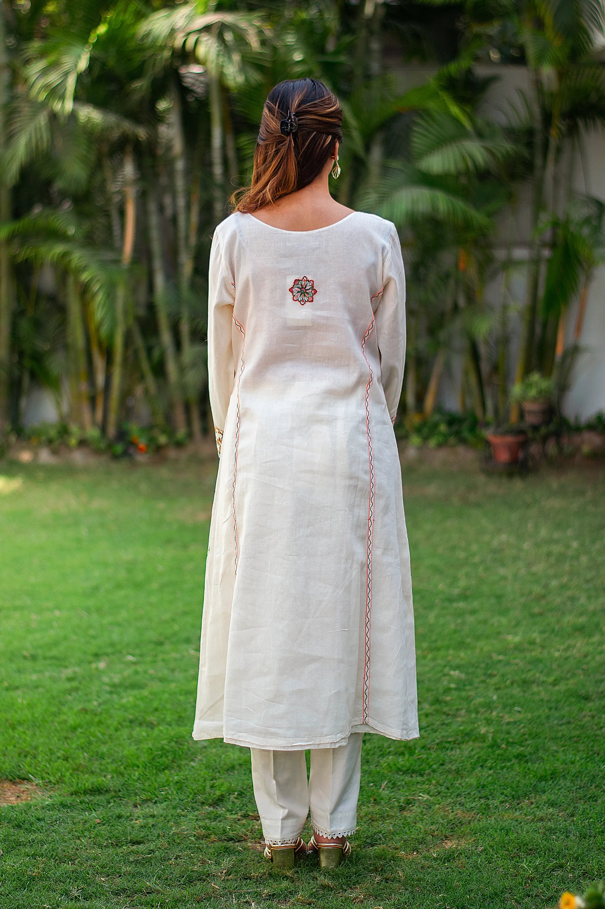 Back view of an Indian model wearing an off-white kurta with Kashmiri embroidery on the back and matching trousers