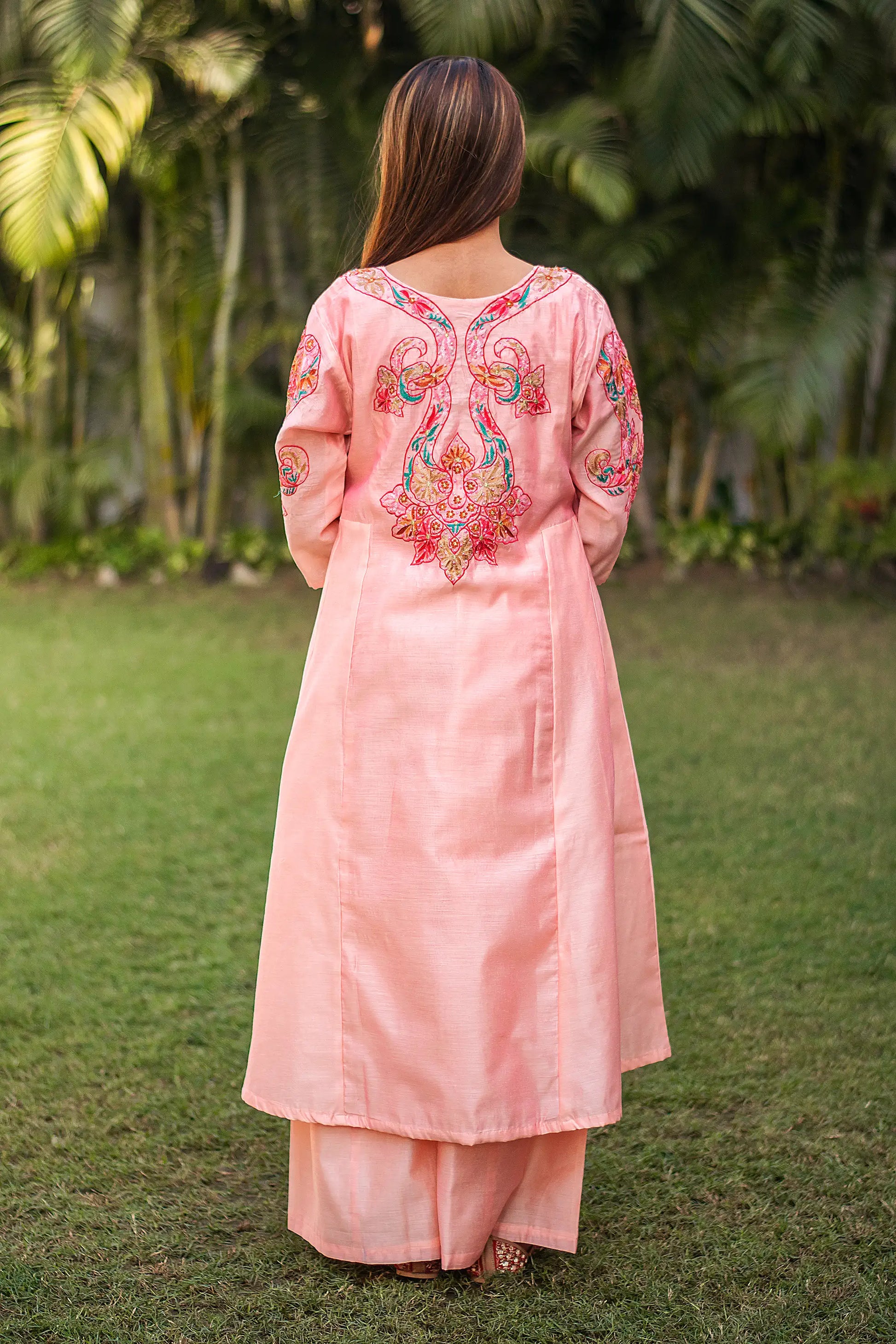 Back view of an Indian model wearing a peach Chanderi kurta with multicoloured embroidery at the back.