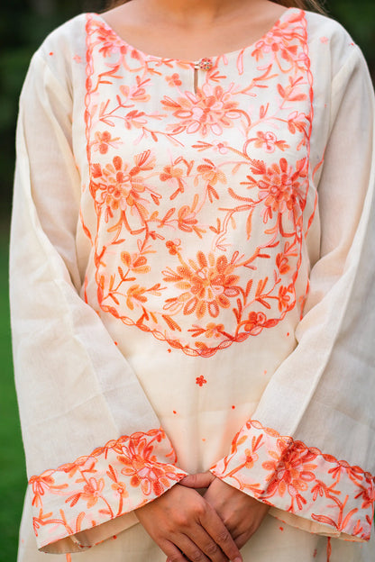 Close-up of peach Kashmiri floral embroidery on the yoke of the off-white kurta.