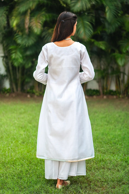 Back view of an Indian model in a white chanderi angarkha kurta featuring kairi (paisley) patchwork, paired with matching white palazzo.