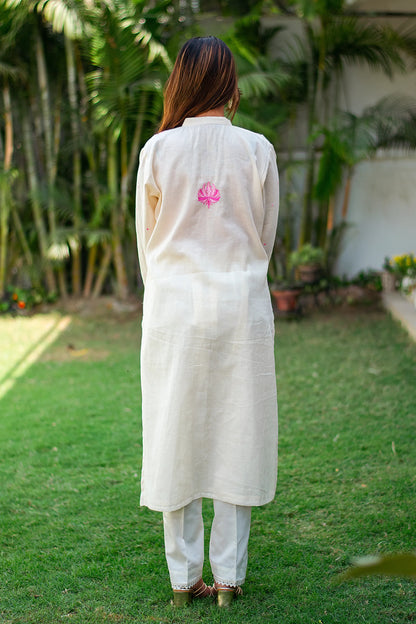 Back view of an Indian model wearing an off-white kurta with pink kashmiri floral motif and plain trousers.