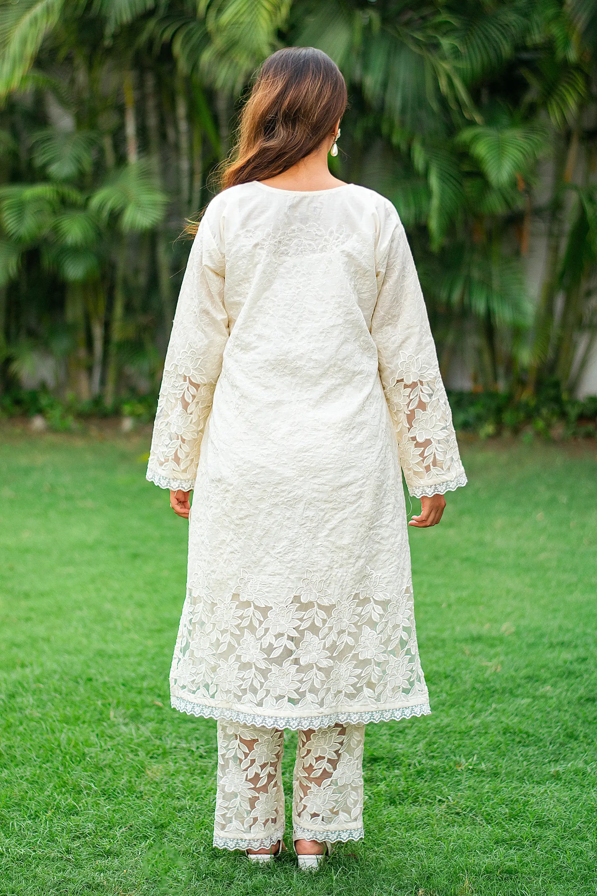 Back view of an Indian model in a white cutwork kurta with full sleeves, paired with matching trousers.