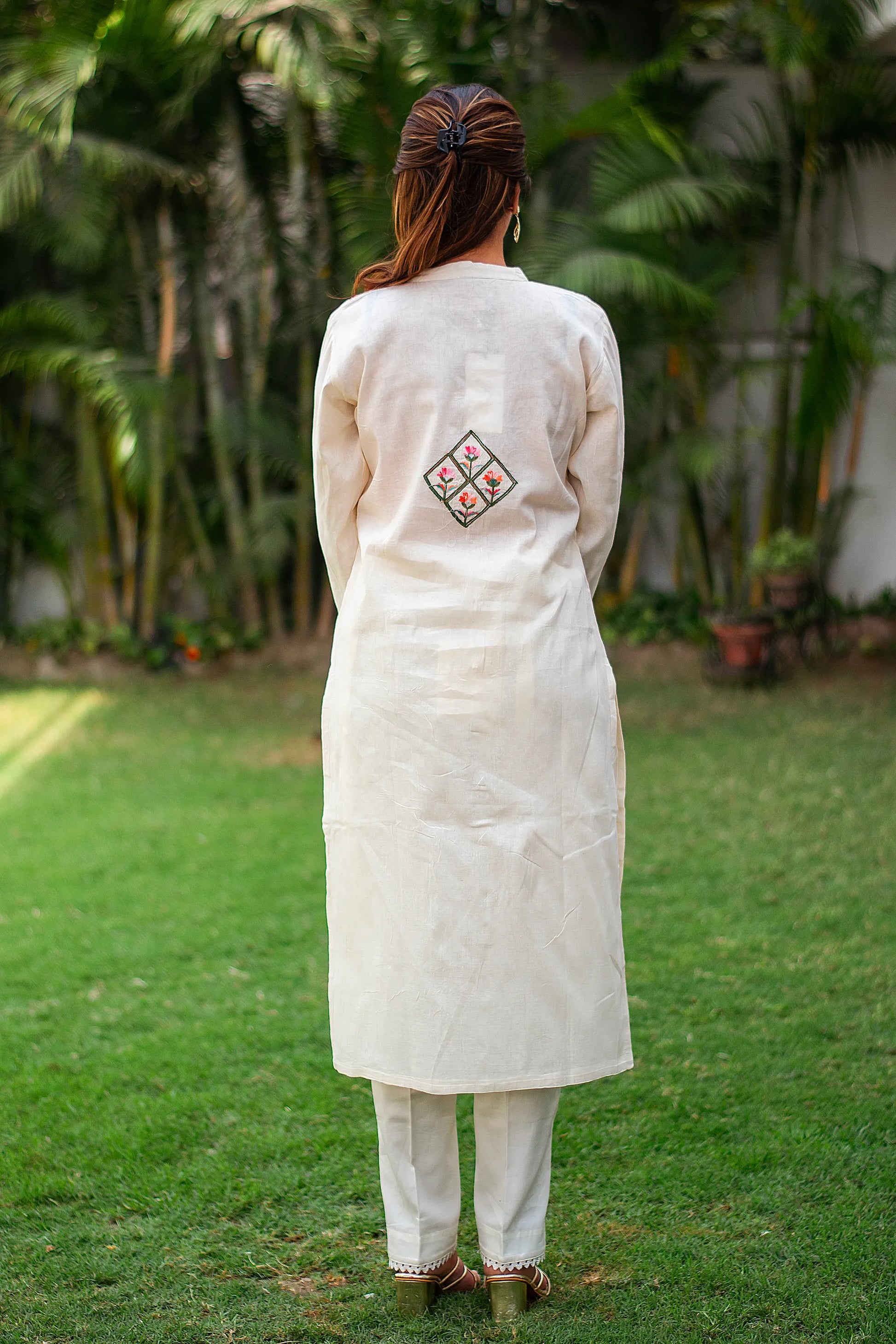 Indian girl in a back pose wearing an off-white cotton kurti with an embroidered motif on the back, without a dupatta.