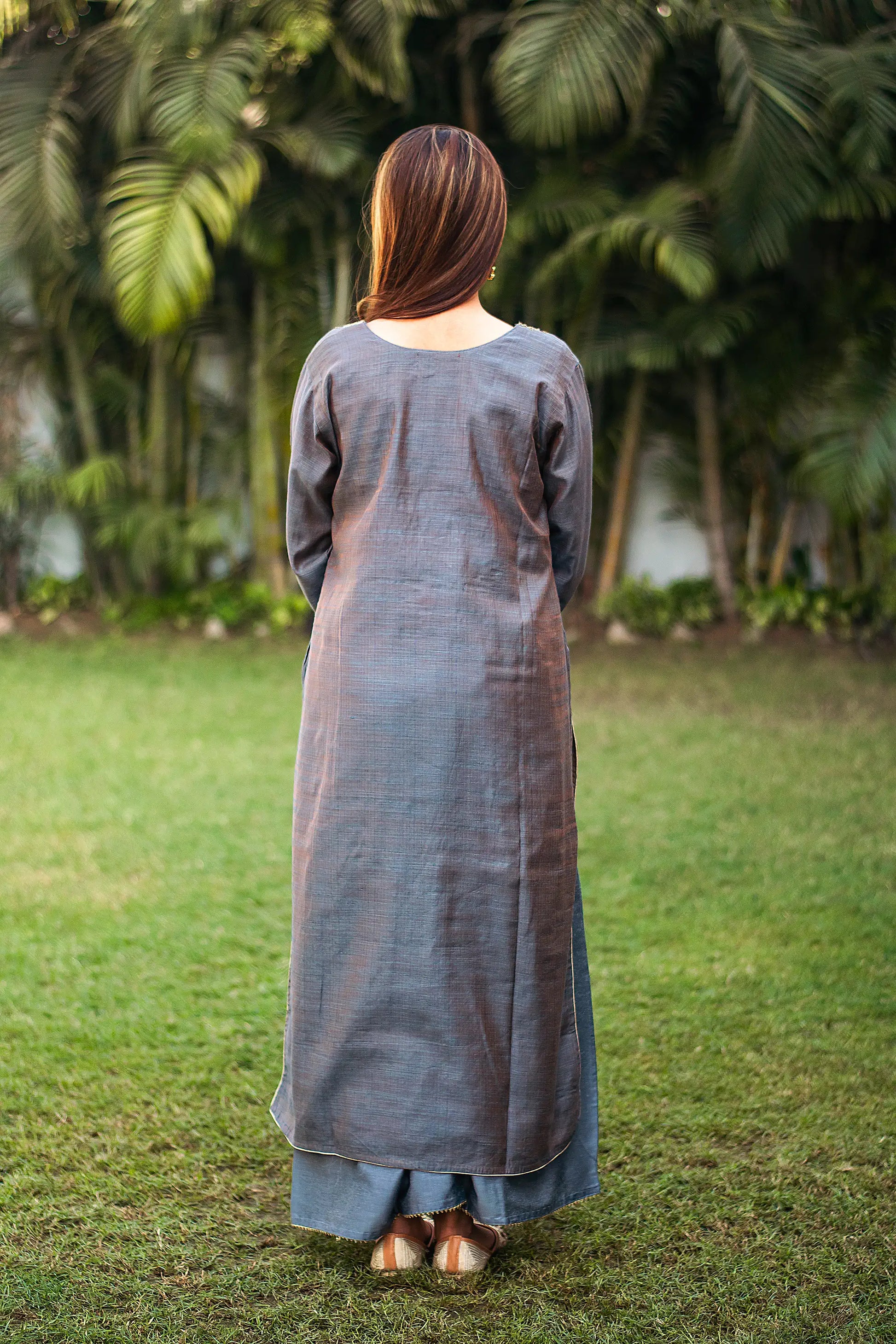 Back view of an Indian model wearing a grey silk kurta with zardozi work.