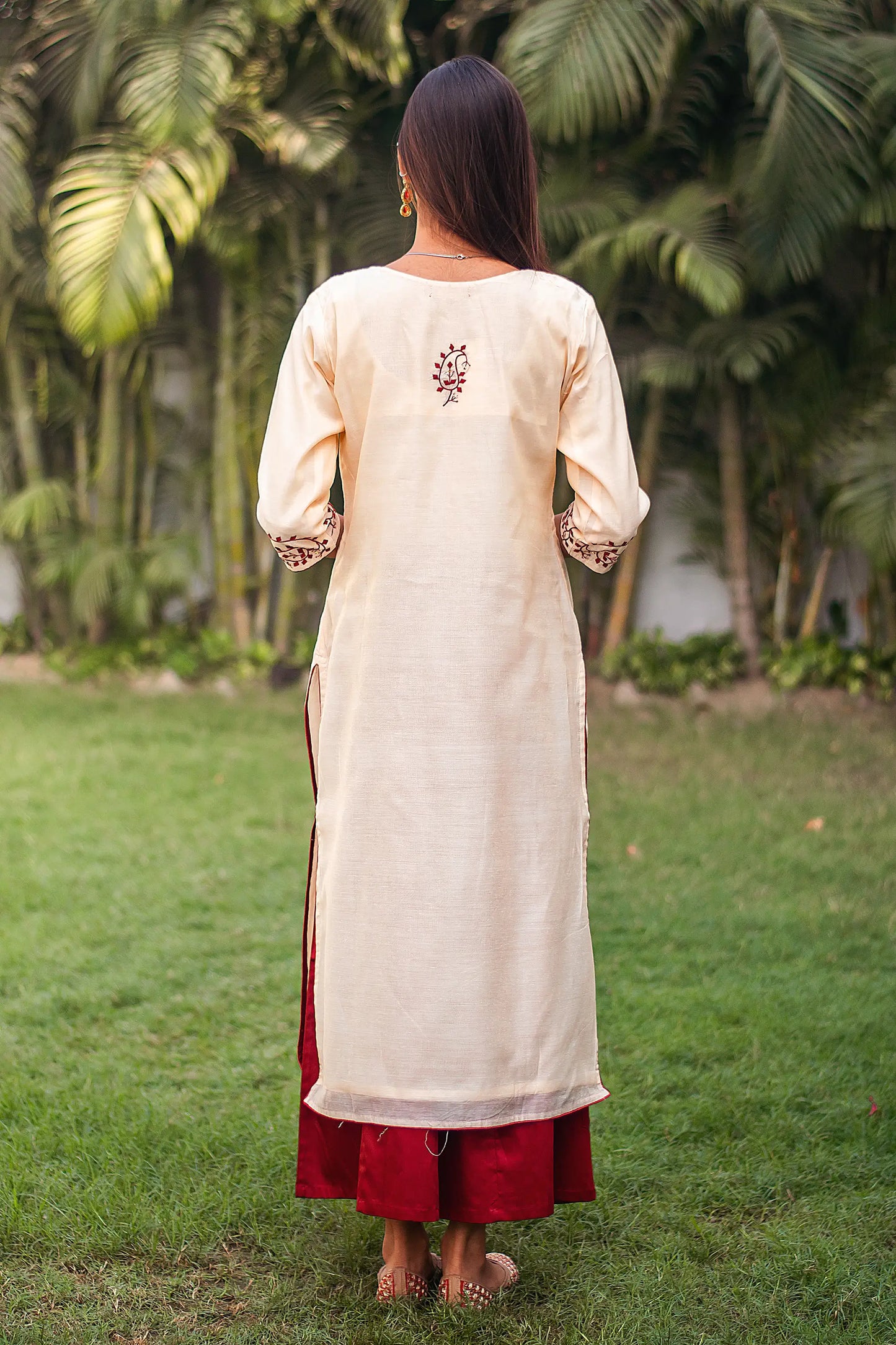 Back view of an Indian model wearing a beige chanderi kurta with a maroon applique motif.