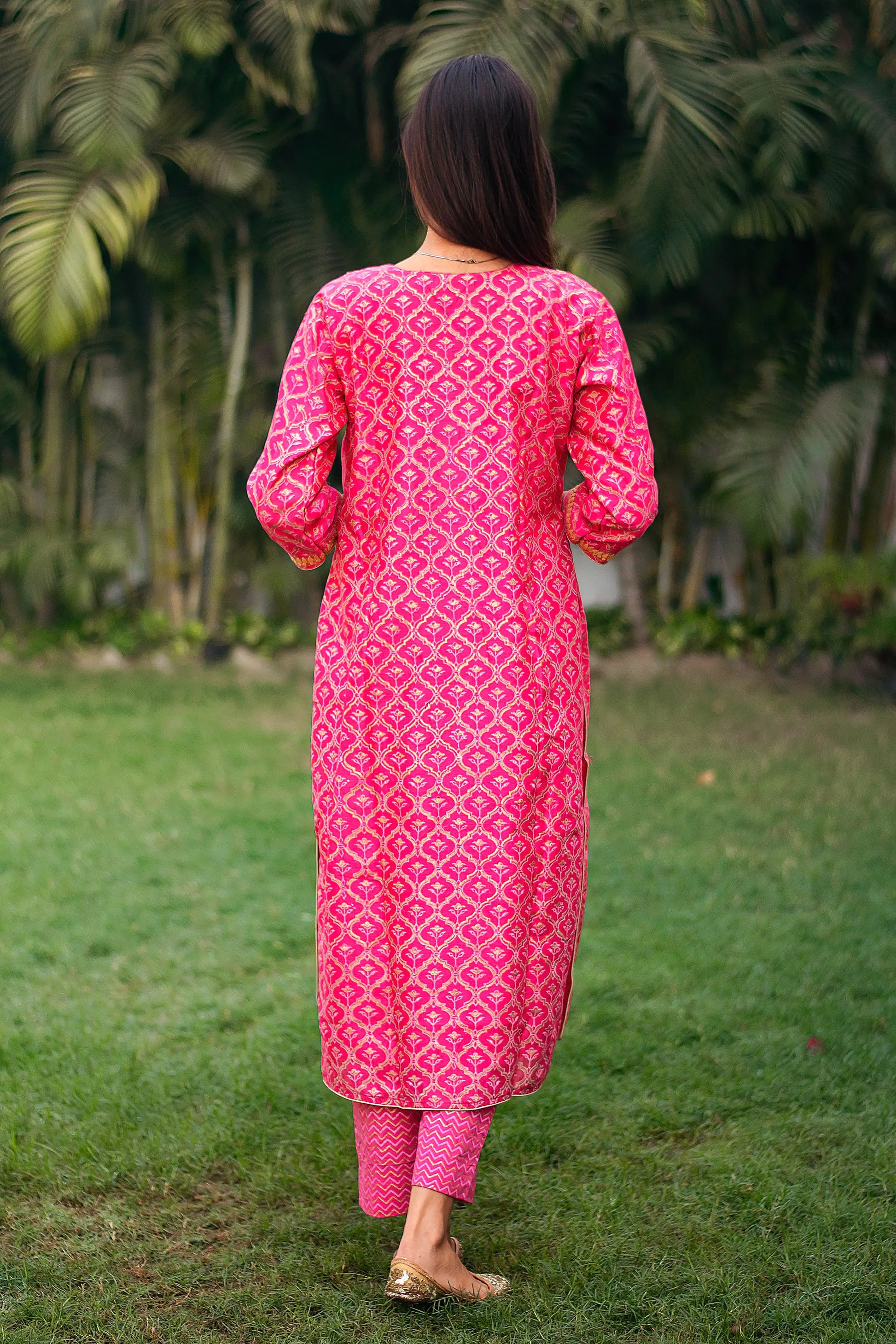 Back view of an Indian model wearing a magenta chanderi kurta with foil-printed Mughal motifs, paired with matching magenta trousers.