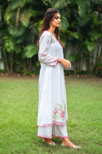 Side profile of an Indian model in a white chanderi angrakha with pink and green embroidery, paired with white palazzo