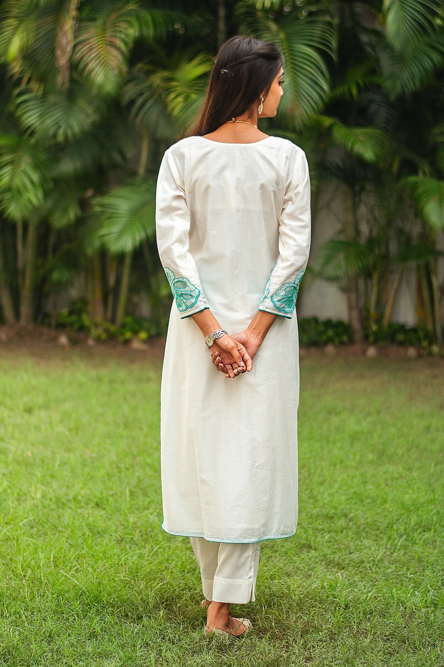 Back view of a model wearing the off-white Chanderi suit with cyan green cutwork, showcasing the full ensemble