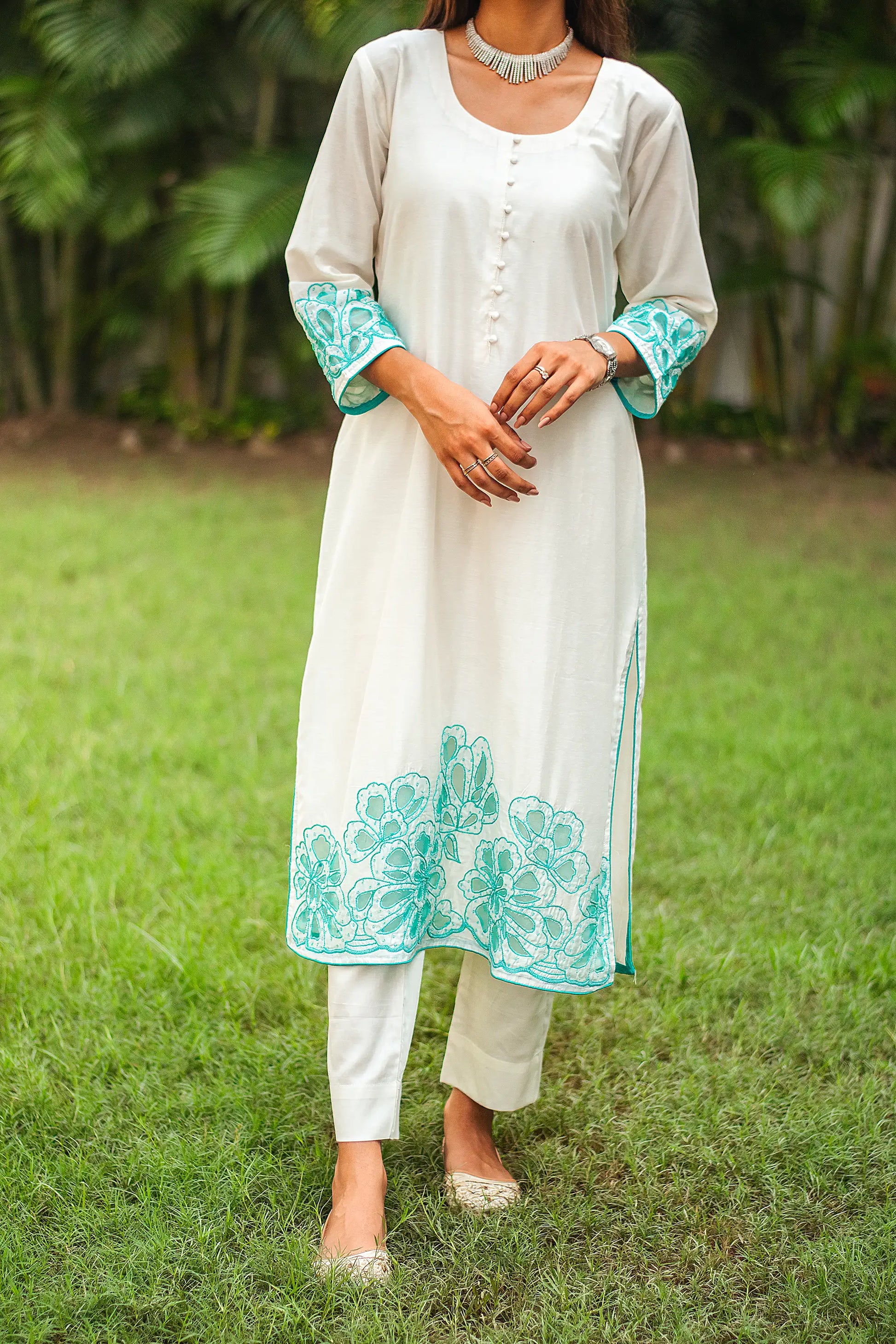 Close-up of the Chanderi fabric and cyan green floral cutwork on the suit, as worn by the model