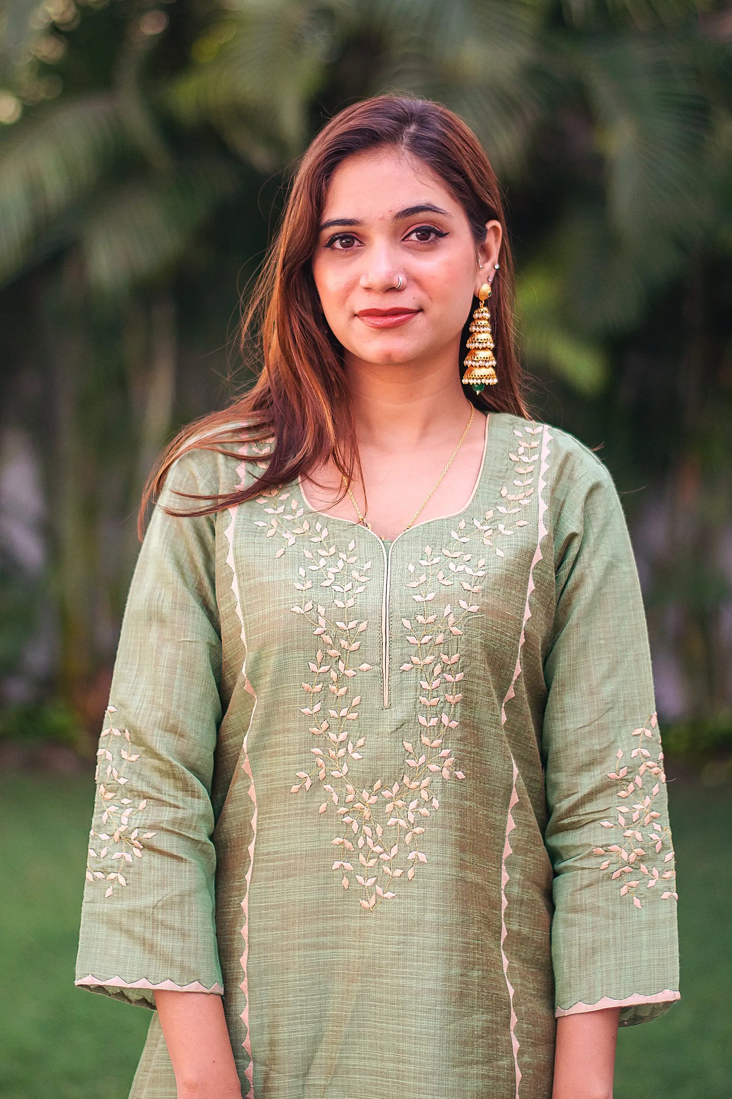 Close-up of the model focusing on the intricate beige applique work on the yoke of the red jute silk kurta.