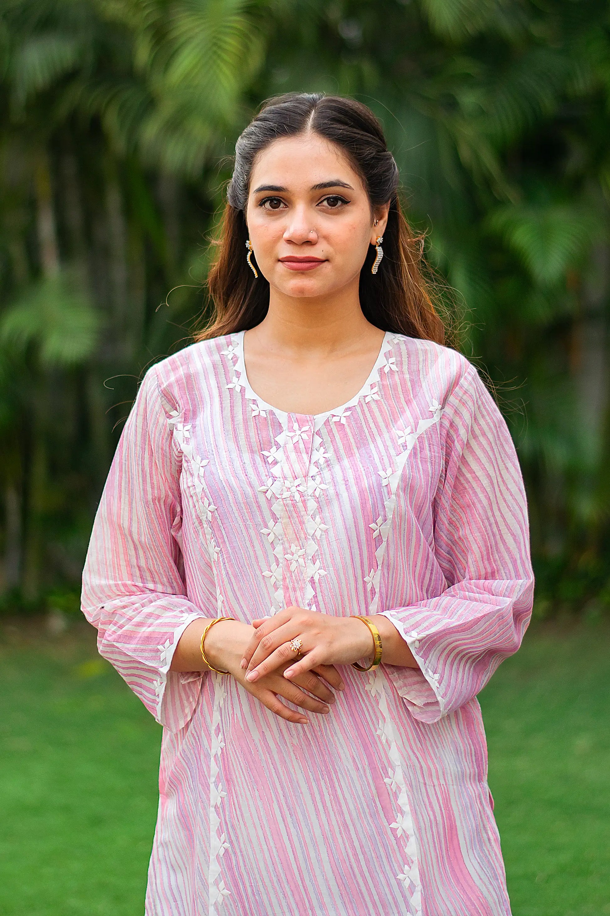 Close-up of an Indian model, highlighting the off-white applique work on the yoke of the pink kurta.