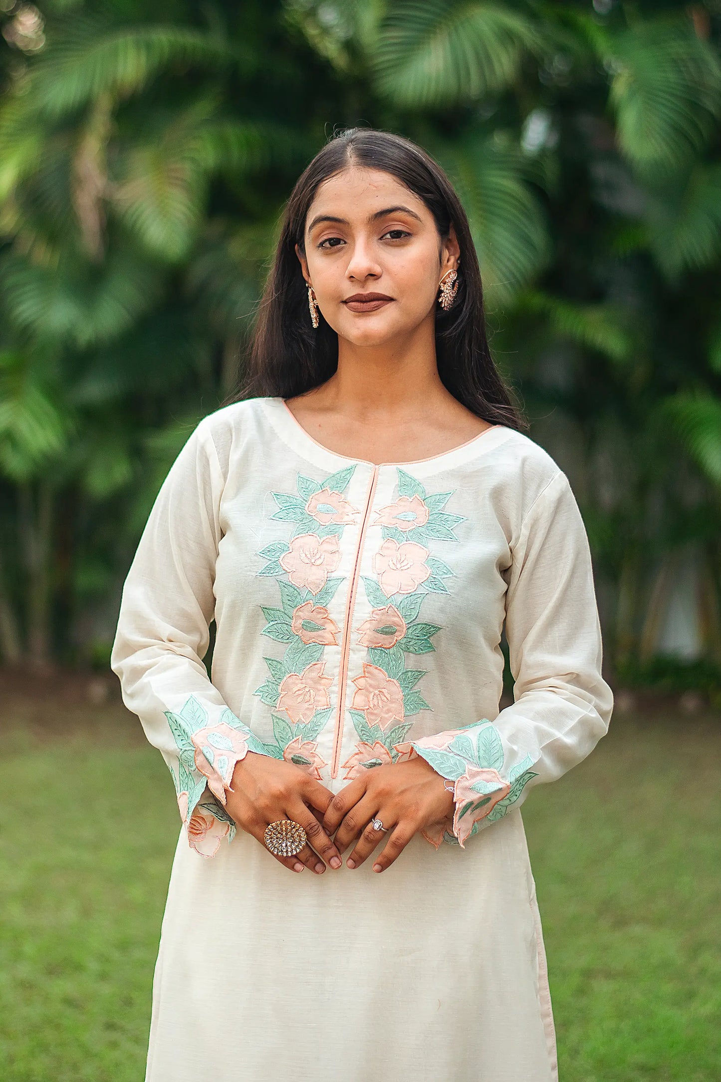 Detailed view of the peach floral patchwork on the yoke of a cream chanderi kurta, worn by an Indian model.