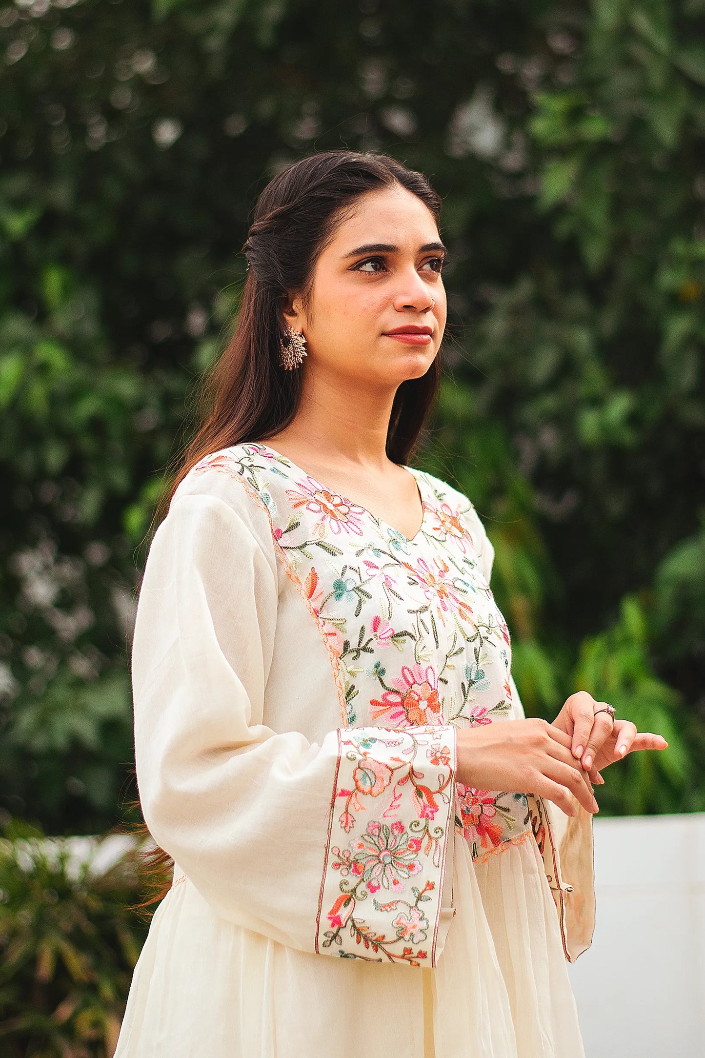 Side pose of a young Indian woman in an off-white cotton Bahaar-e-Chinaar frock kurta set with matching palazzo pants and dupatta.