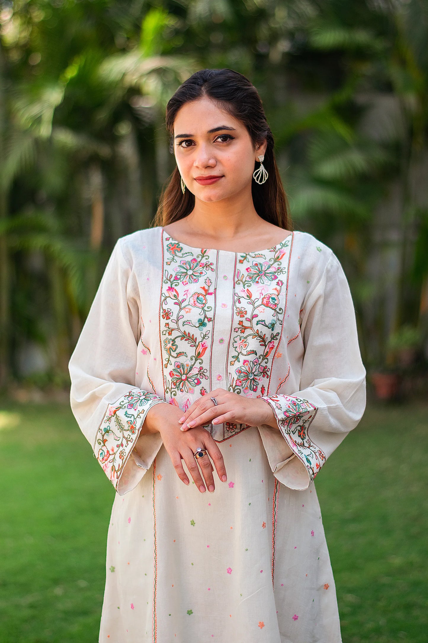 Close-up of an Indian model, focusing on the floral Kashmiri embroidery on the yoke of the off-white kurta.