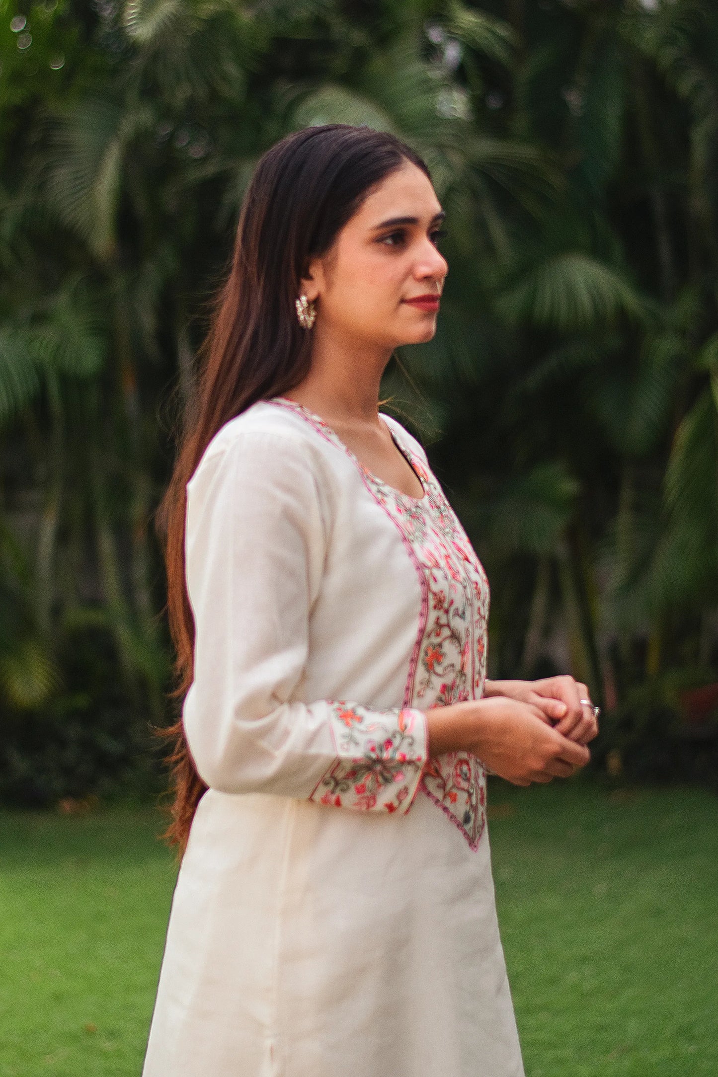 Indian model in a side pose wearing an off-white Kashmiri embroidered kurta and trousers, without the dupatta