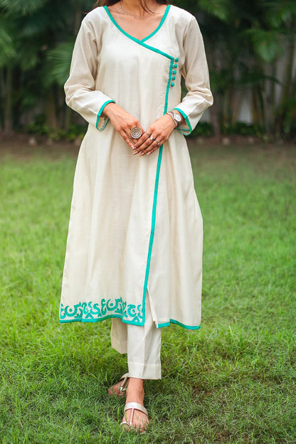 Close up view of a model wearing the beige chanderi angrakha set capturing the beige chanderi angrakha with green calligraphy patchwork and matching trousers