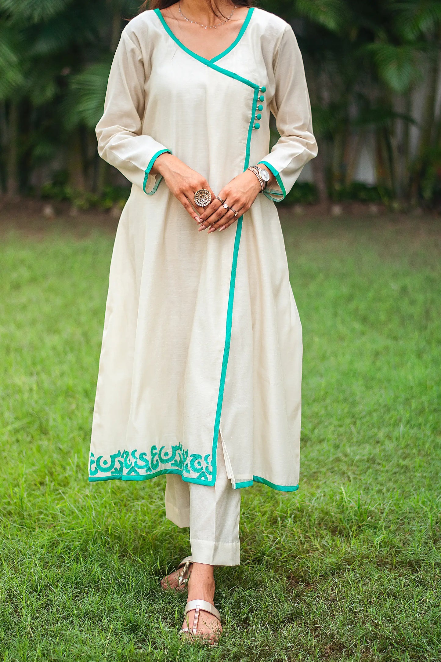 Close up view of a model wearing the beige chanderi angrakha set capturing the beige chanderi angrakha with green calligraphy patchwork and matching trousers