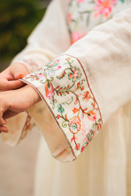 Close-up of the sleeve of an off-white cotton Bahaar-e-Chinaar frock kurta, showcasing the intricate Kashmiri embroidery in vibrant hues.