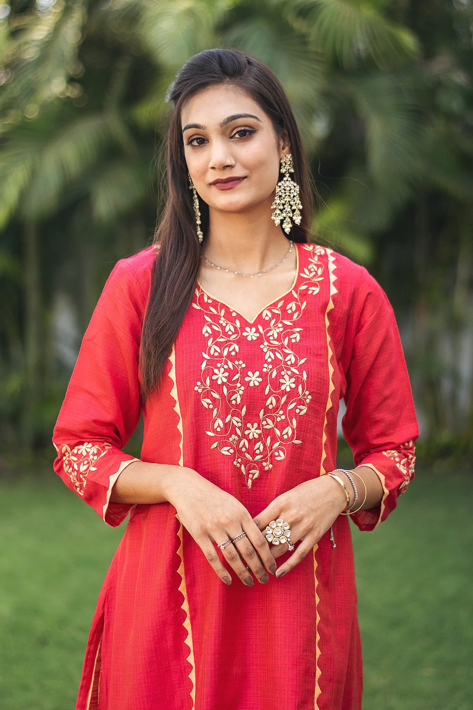 Close-up of the model focusing on the intricate beige applique work on the yoke of the red jute silk kurta.