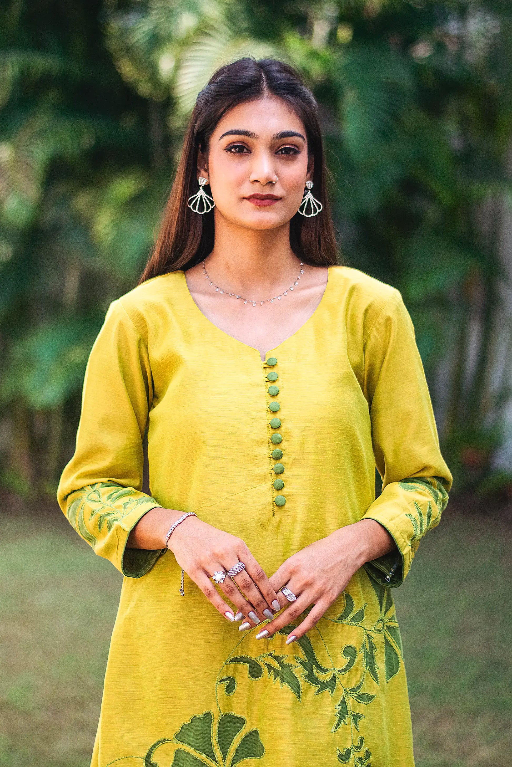 Upper half front view of a model wearing the cutwork kurta set, featuring a yellowish-green chanderi kurta with green floral cutwork and dark green trousers