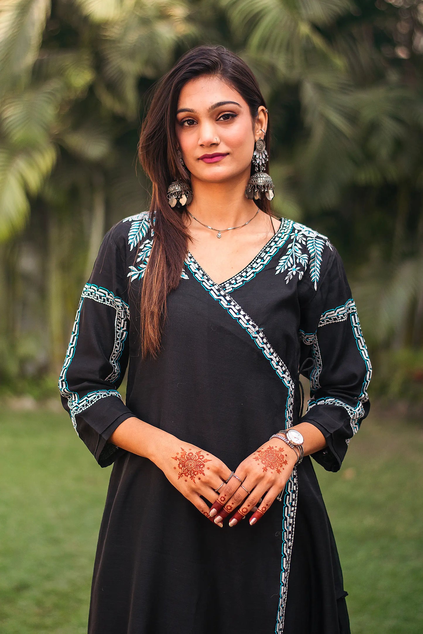 Close-up of the model focusing on the white floral embroidery on the upper half of the black chanderi angrakha kurta.