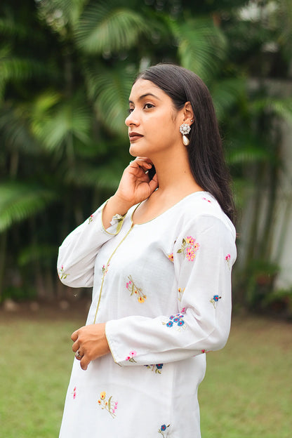 Side view of an Indian model in a white chanderi kurta with colorful resham embroidery. 