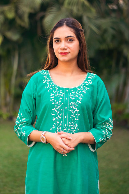 Indian girl poses where half of  front of the green Chanderi kurta with applique work is visible.