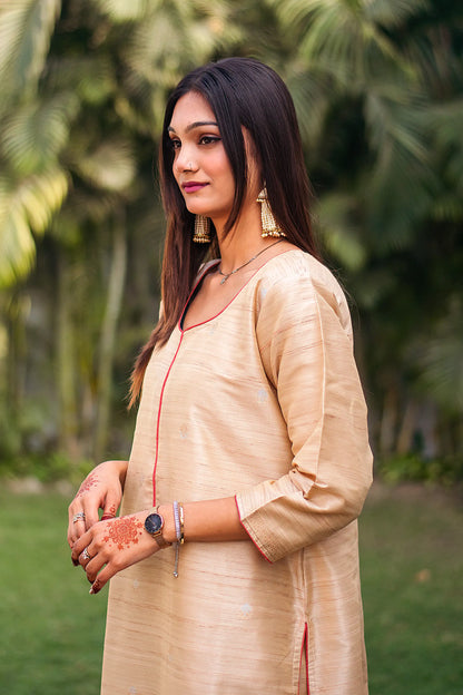  Side view of an Indian model in a beige silk kurta with colorful resham weave around the borders