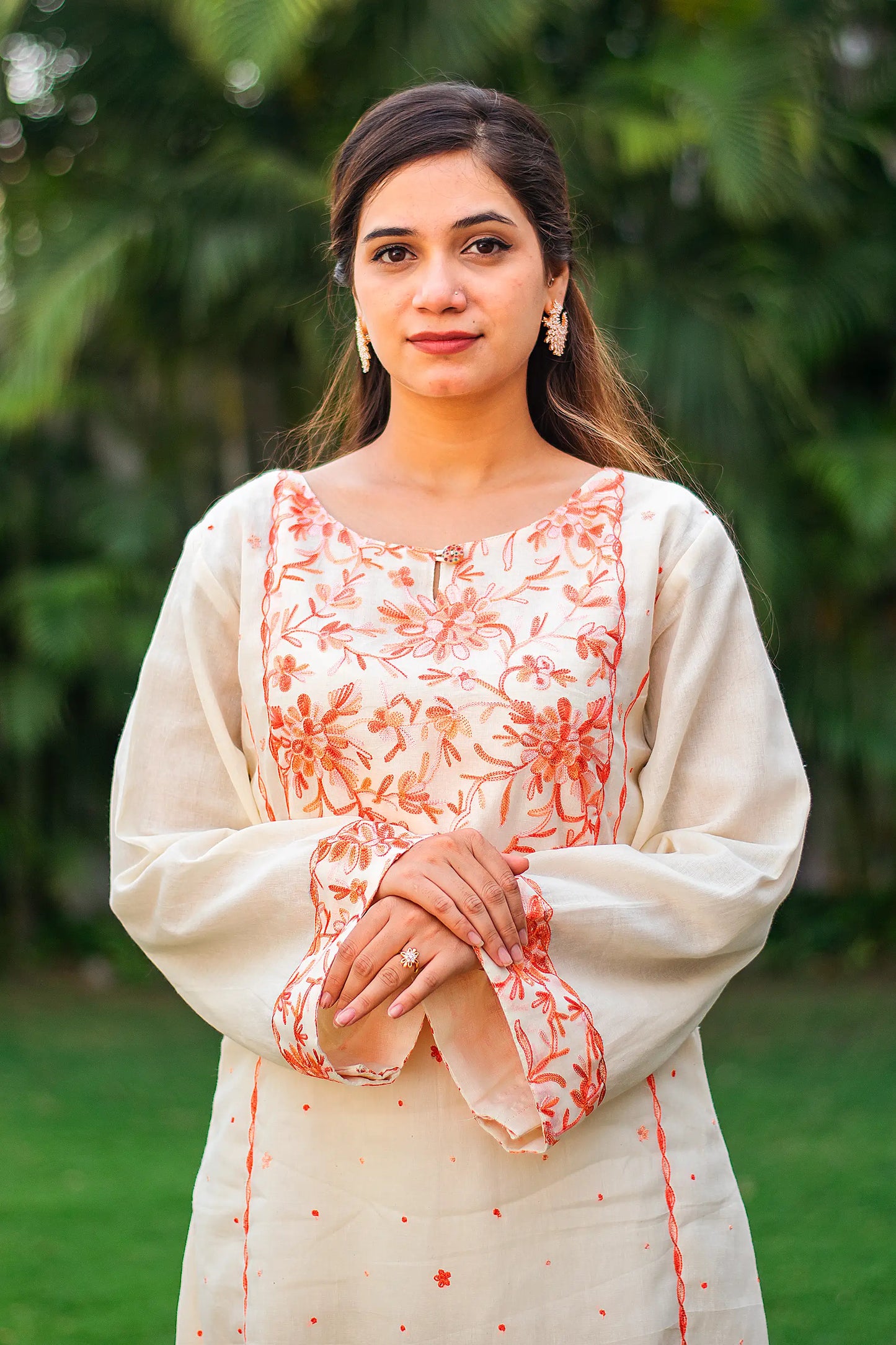 Close-up of an Indian model, focusing on the peach floral Kashmiri embroidery on the yoke of the off-white kurta.