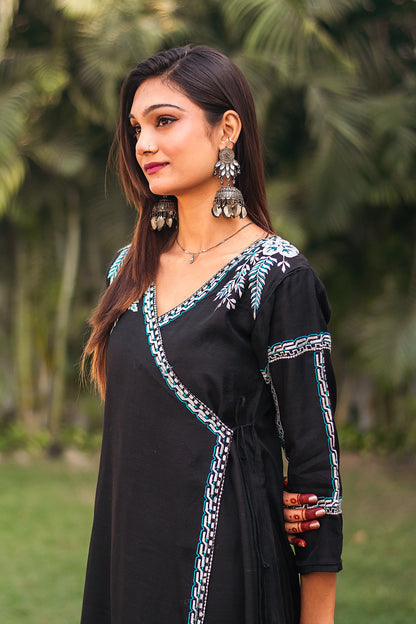 Side view of an Indian model in a black chanderi angrakha kurta with white and blue resham embroidery.