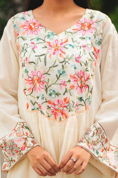 Close-up of a young Indian woman wearing an off-white cotton Bahaar-e-Chinaar frock kurta, showcasing the intricate Kashmiri embroidery on the neckline.