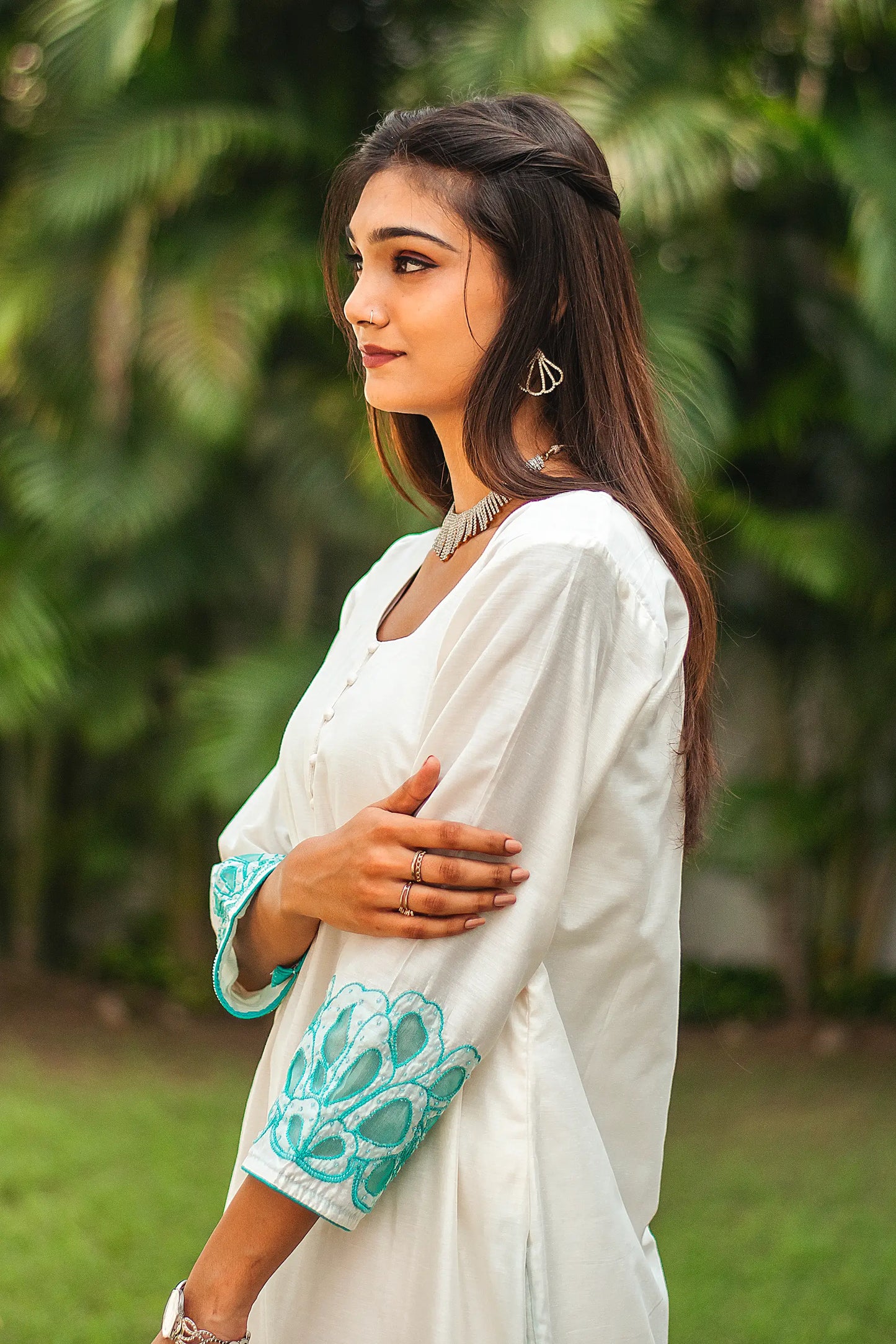 Left side upper half view of a model wearing the off-white Chanderi suit with cyan green floral cutwork, highlighting the suit's elegant silhouette