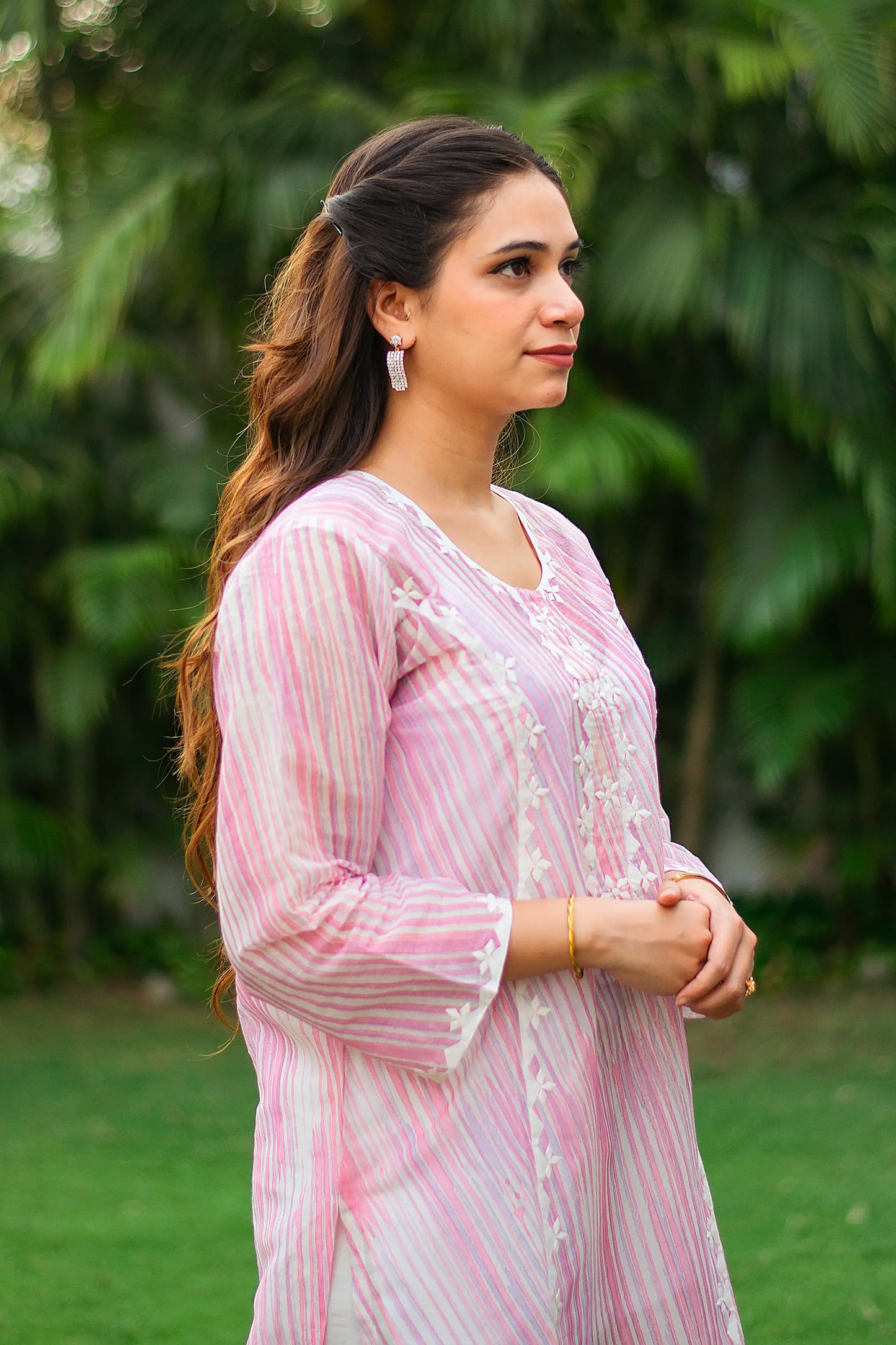 Indian model in a side profile, wearing a pink print applique work kurta.