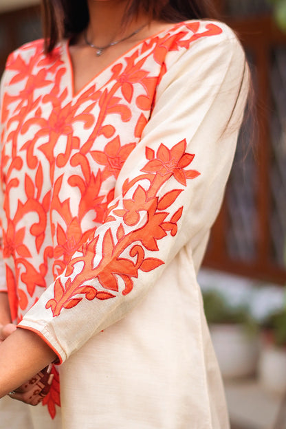 Close-up of the orange patchwork detailing on the sleeve cuff of the beige chanderi kurta.