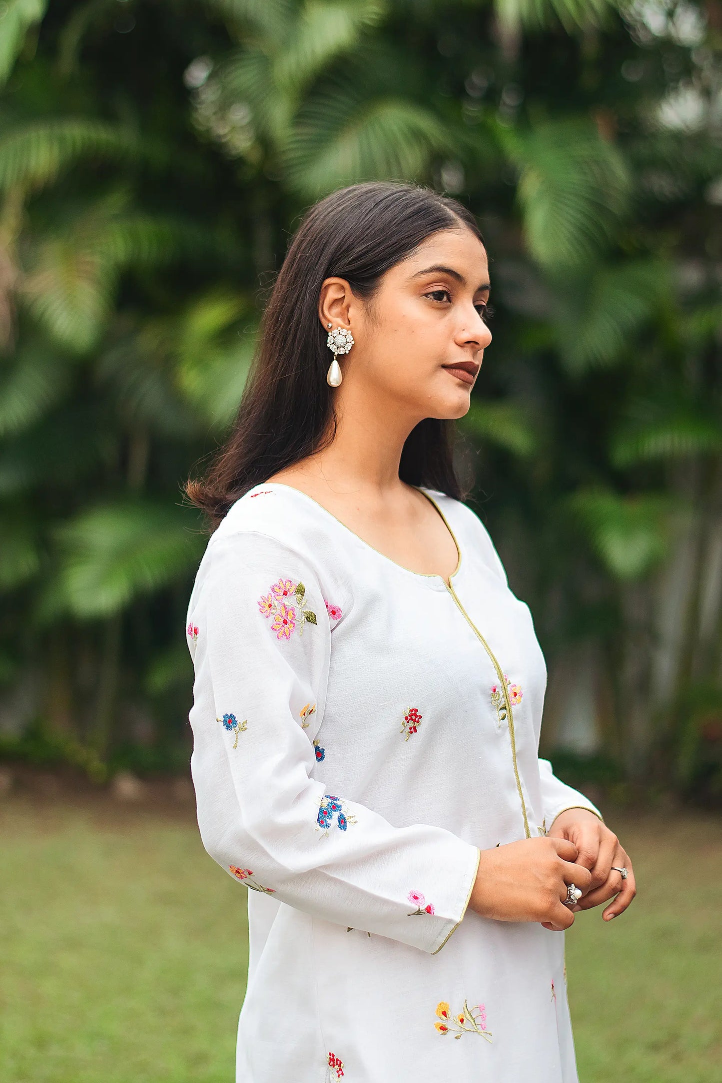 Indian model in a side pose wearing a white chanderi kurta with floral resham work.