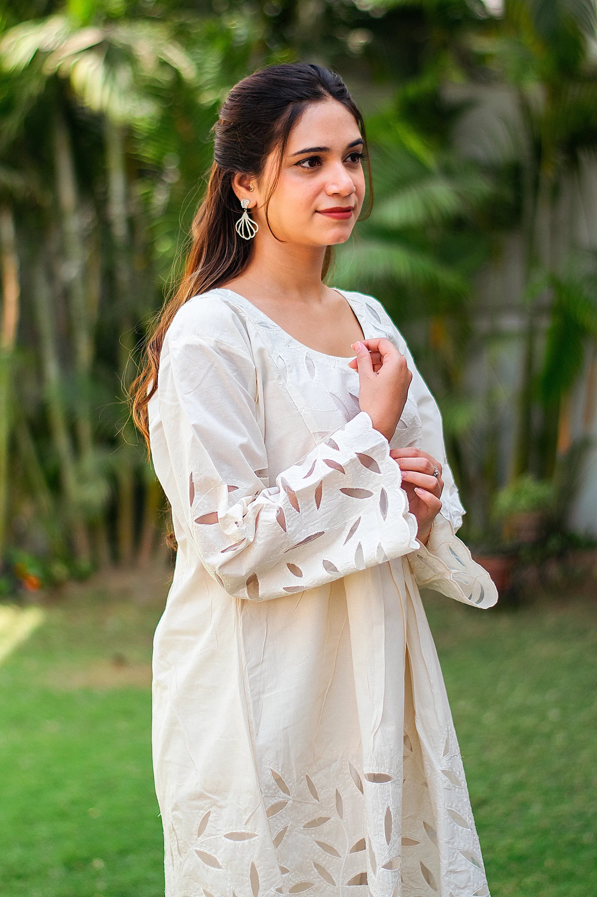 Side pose of an Indian model in a floral cutwork embroidered off-white kurta. 