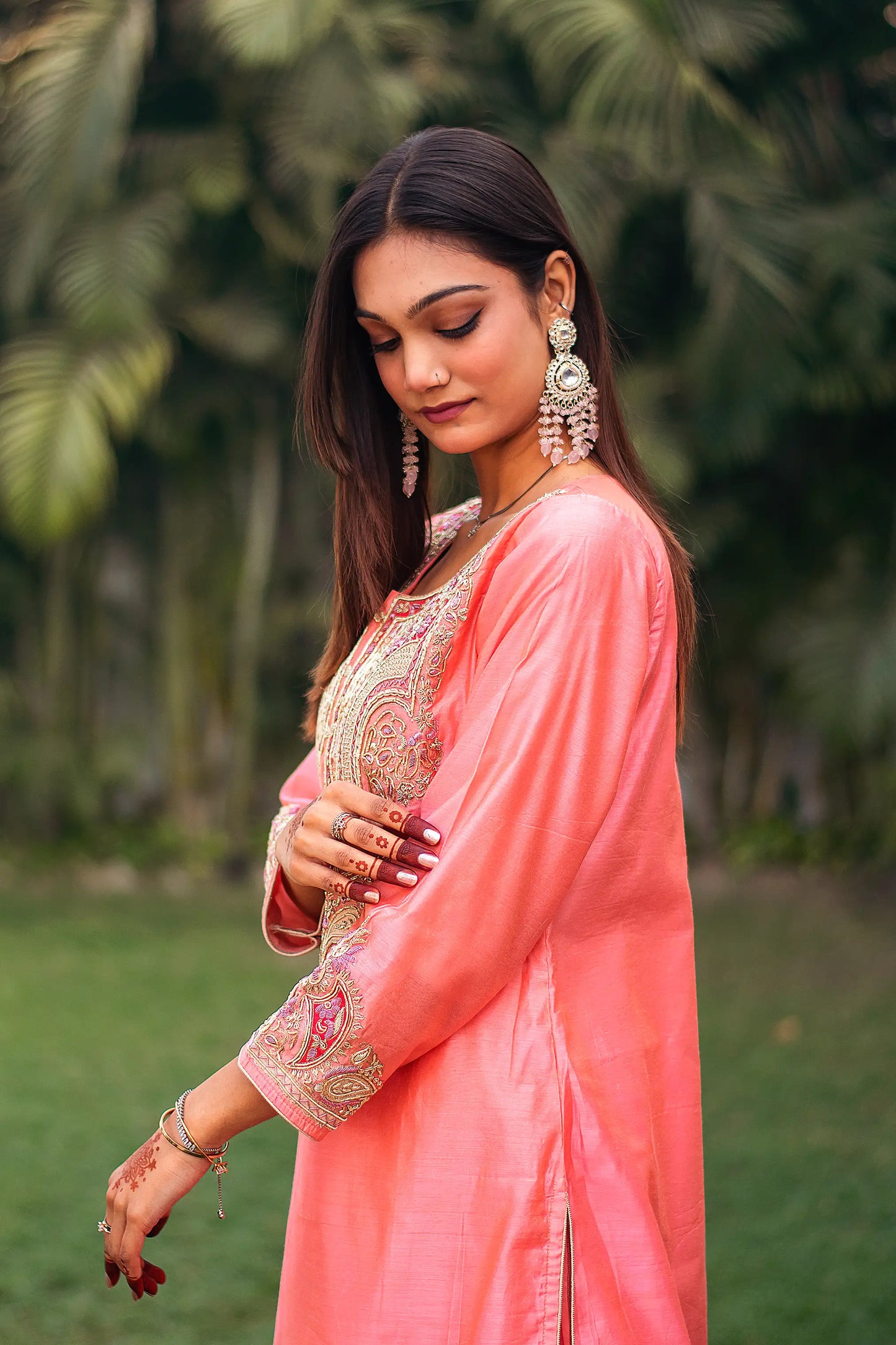  Indian model in a side pose, highlighting the zardozi motifs on the peach kurta.