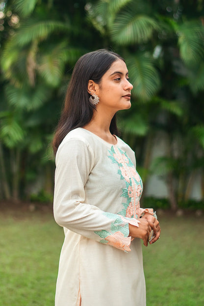 Side profile of an Indian model wearing a cream chanderi kurta featuring intricate peach patchwork flowers.